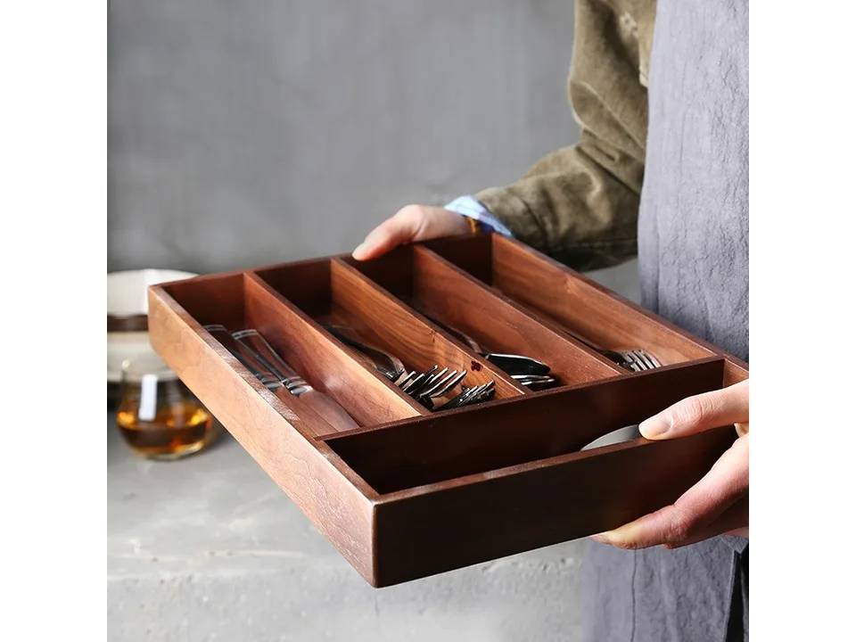 A person holding the wooden cutlery organizer tray.