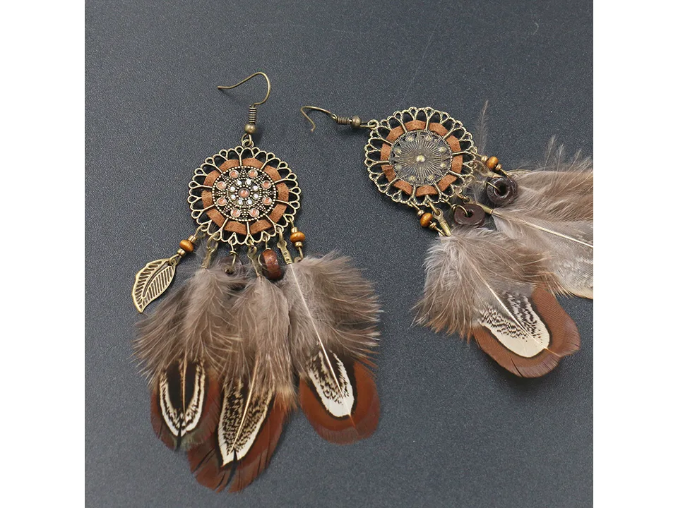 A pair of bohemian feather dreamcatcher earrings on a dark surface.