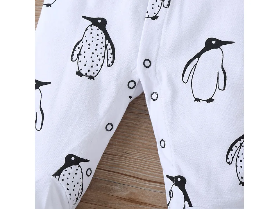 Close-up of the snap buttons on the white penguin-print baby jumpsuit.