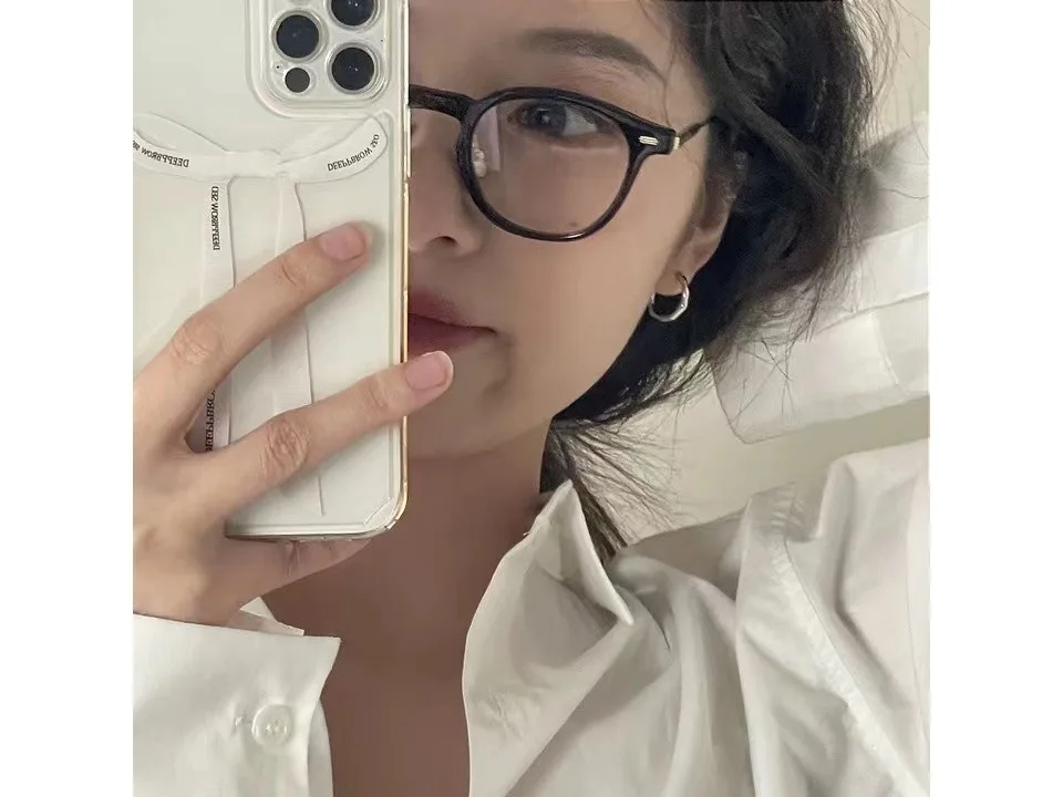 Person wearing the silver hoop earring while holding a phone.
