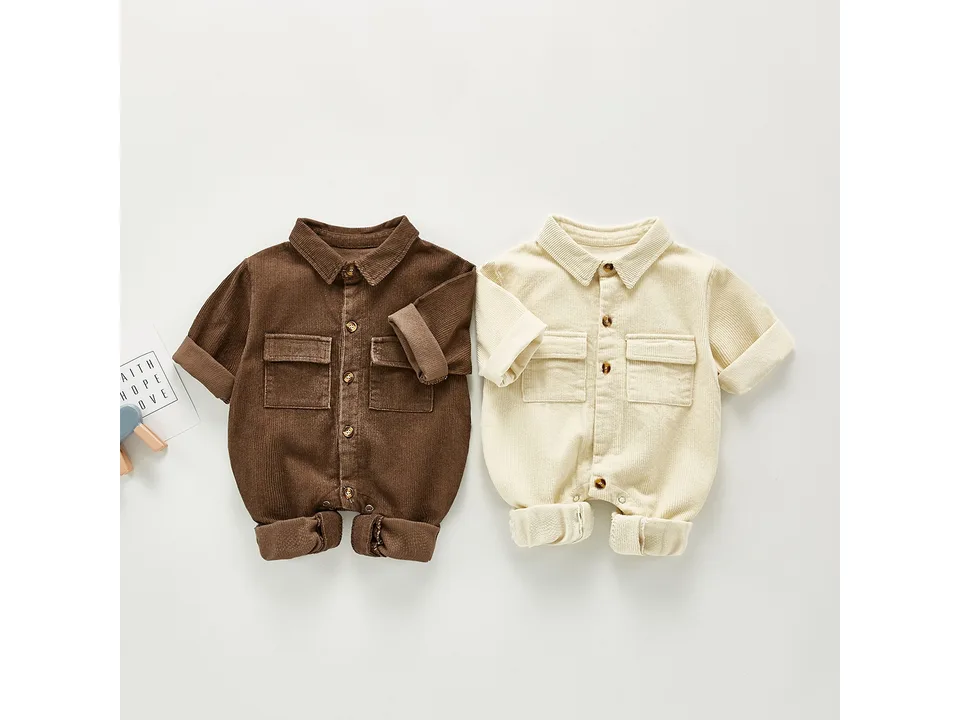 Two baby corduroy rompers, one brown and one cream, laid flat on a white background.