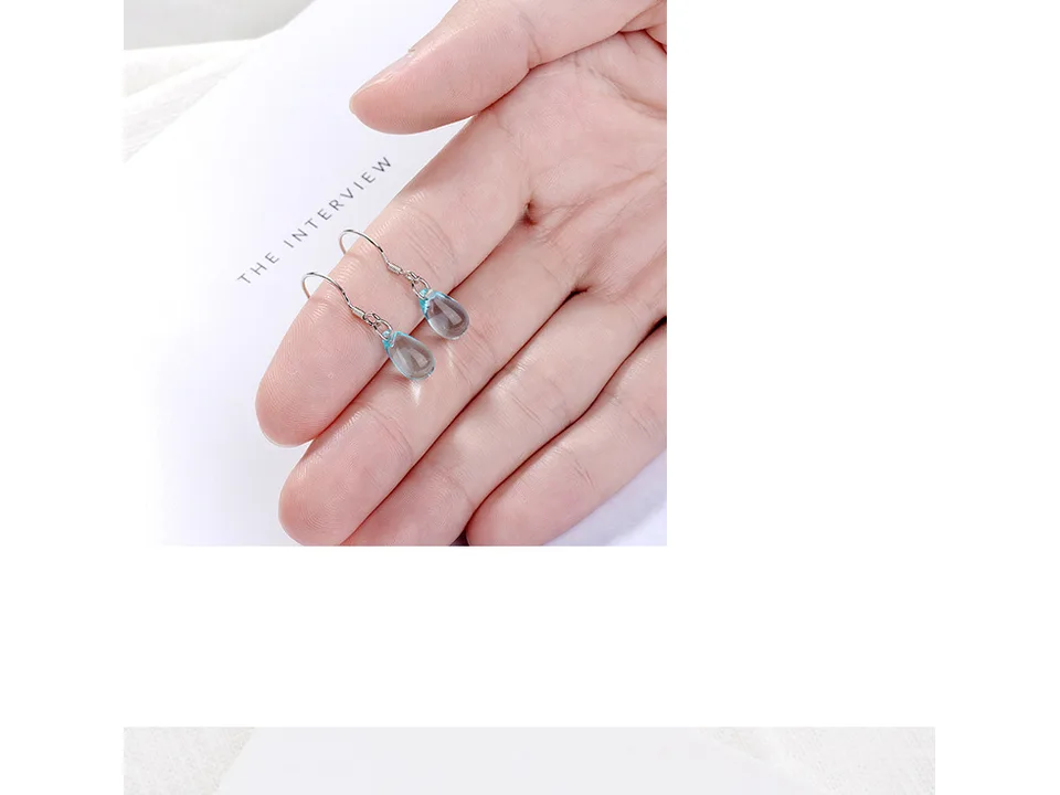Blue crystal drop earrings held in a person's palm.