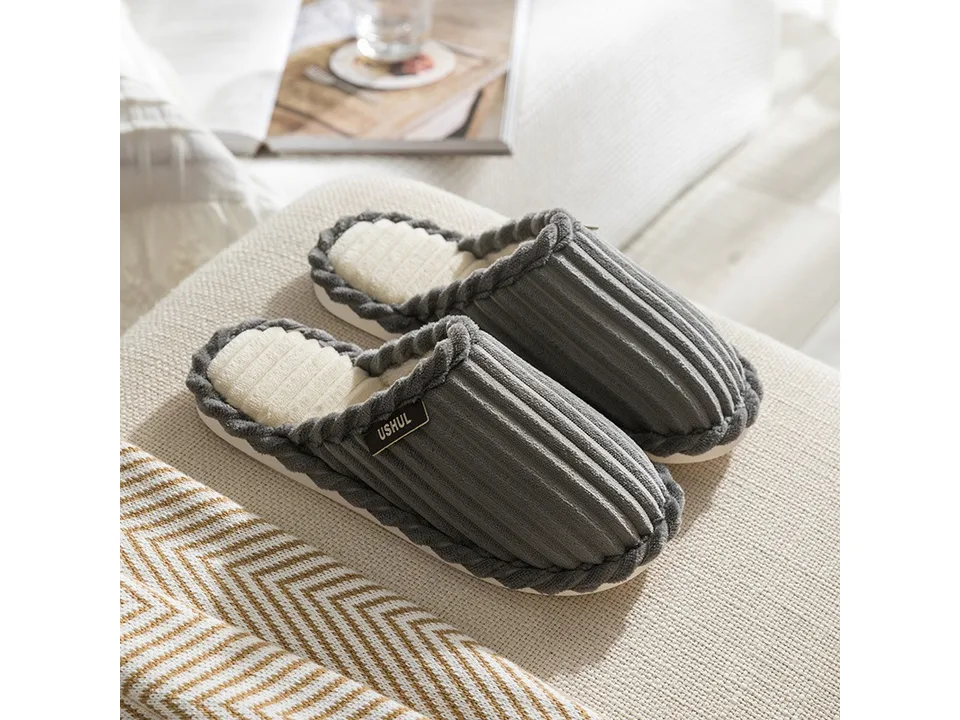 A pair of grey corduroy slippers with a plush lining.