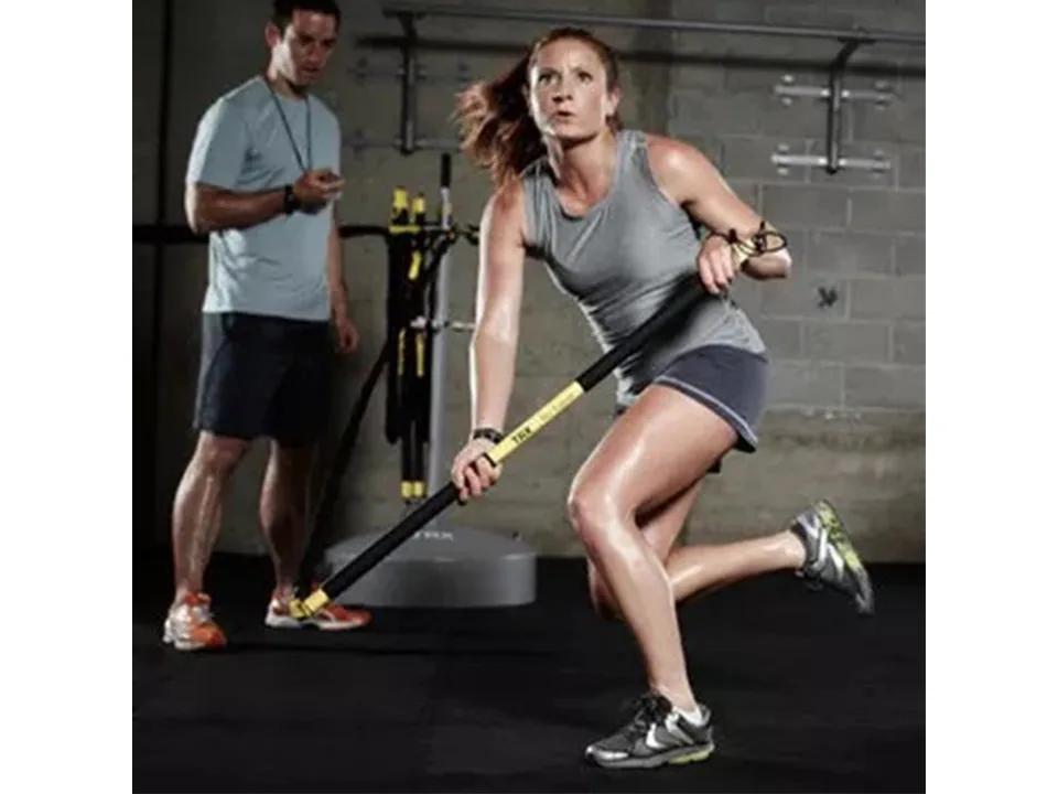 A woman using the resistance training bar in a gym.