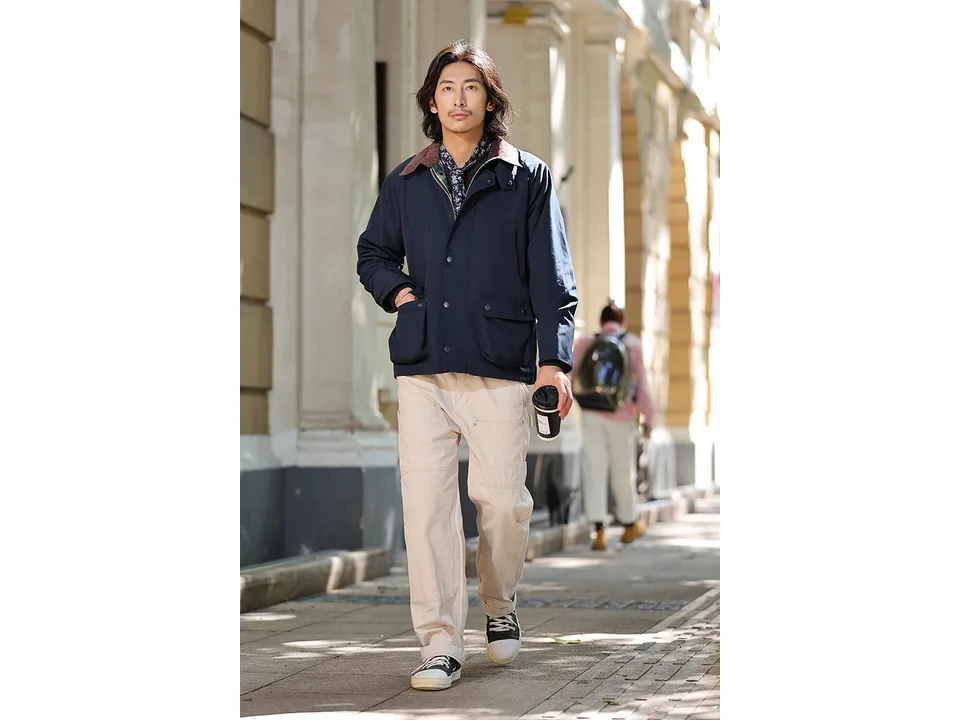 A man wearing the navy blue field jacket while walking outdoors.