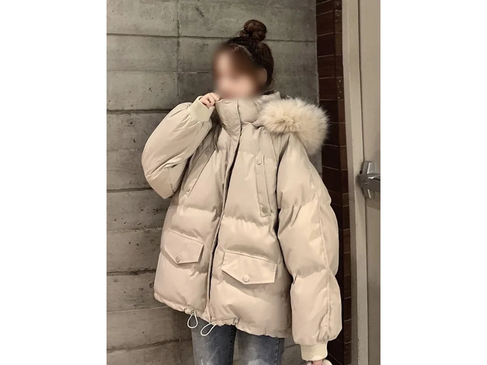 A woman wearing a beige hooded puffer parka, side view.