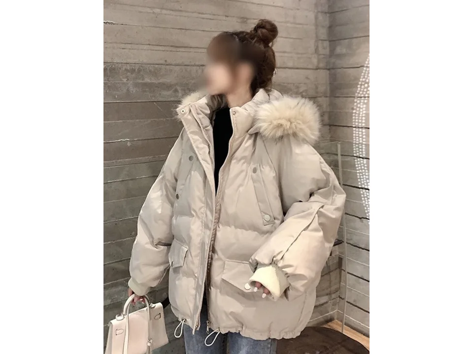 A woman wearing a beige hooded puffer parka with faux fur trim.