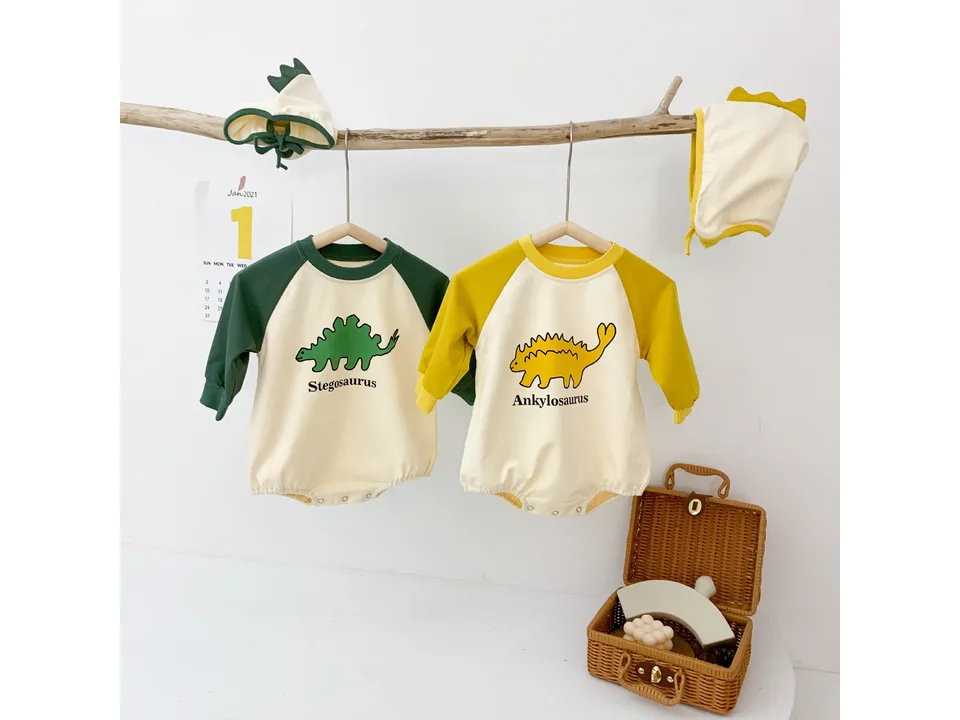 Two baby jumpsuits, one green with a Stegosaurus print and one yellow with an Ankylosaurus print, with hoods.
