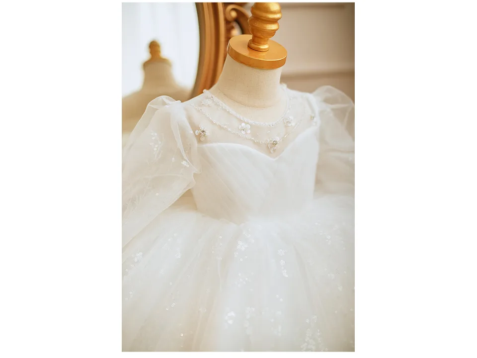 Close-up of the white dress bodice showing pearl and floral embroidery details.