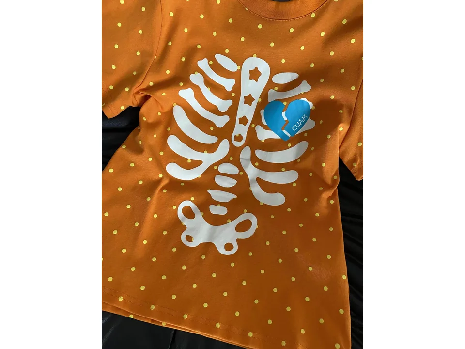 Close-up of the skeleton ribcage print with a blue broken heart on an orange polka dot t-shirt.