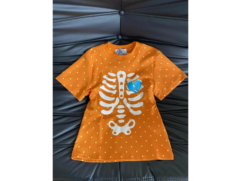 Orange t-shirt with a white skeleton ribcage print and yellow polka dots.