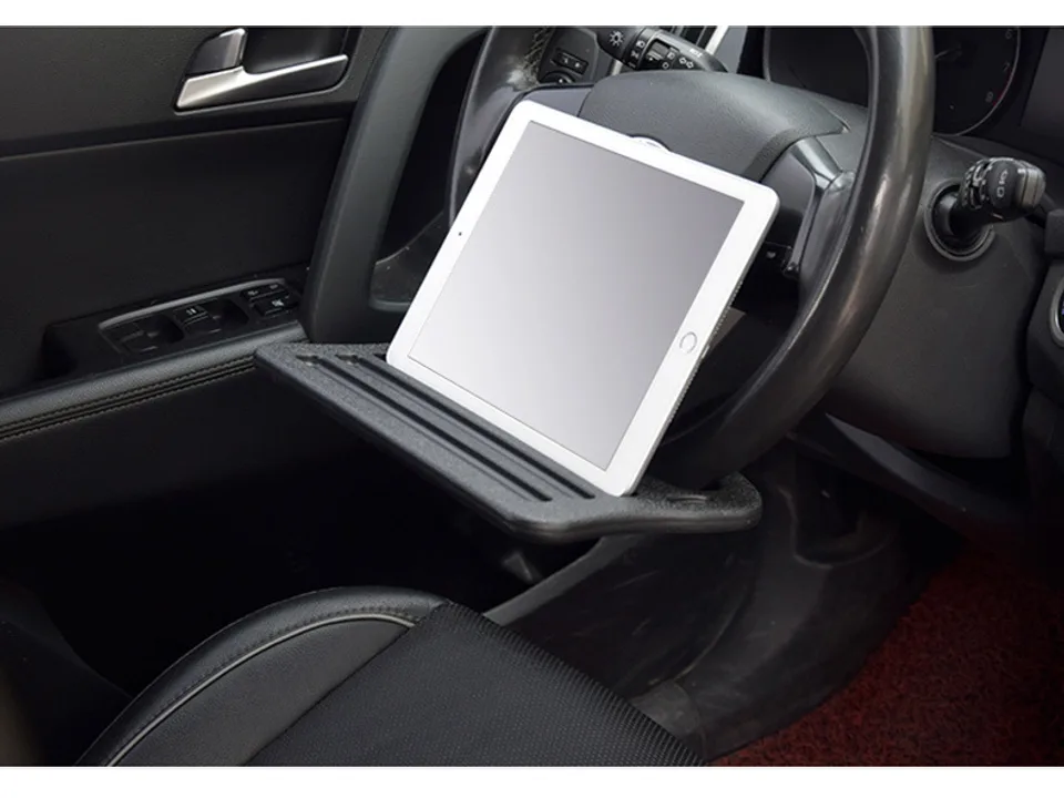 A car steering wheel tray holding a tablet computer.