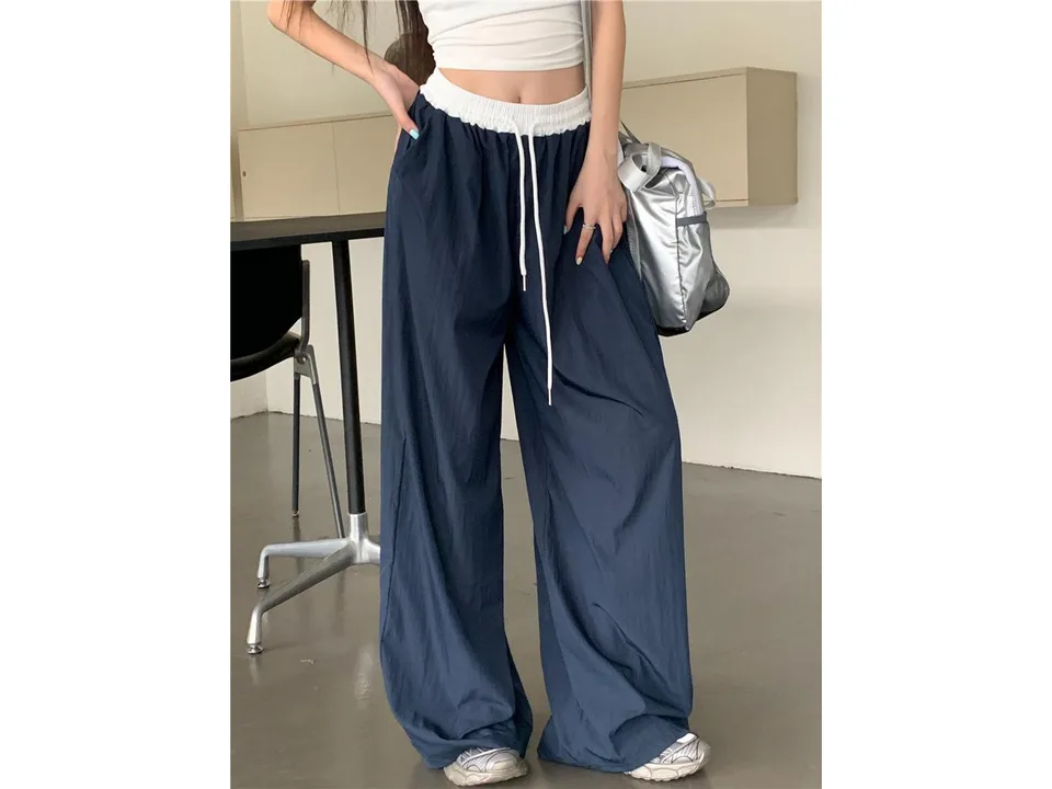 A woman wearing wide-leg trousers with a white elastic waistband.