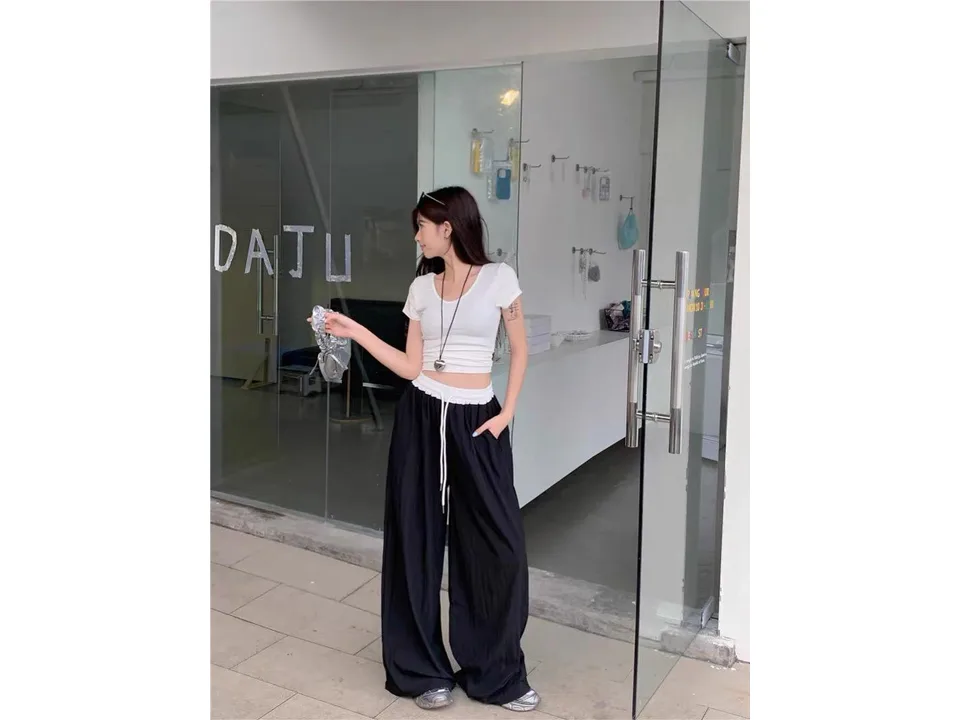 A woman wearing wide-leg trousers with a white elastic waistband.