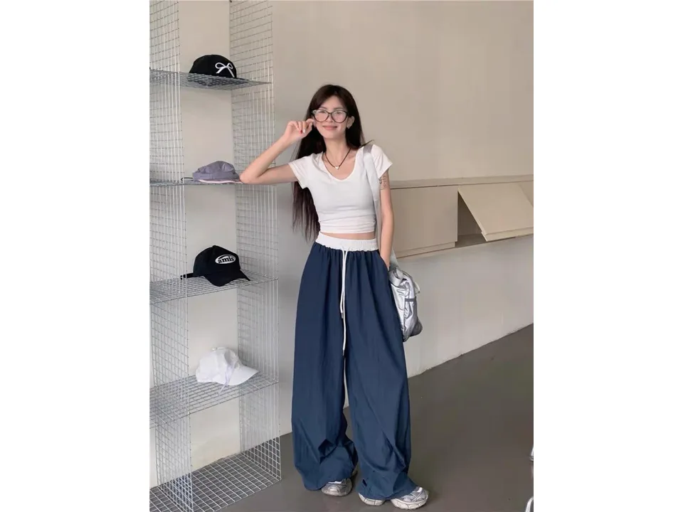 A woman wearing wide-leg trousers with a white elastic waistband.