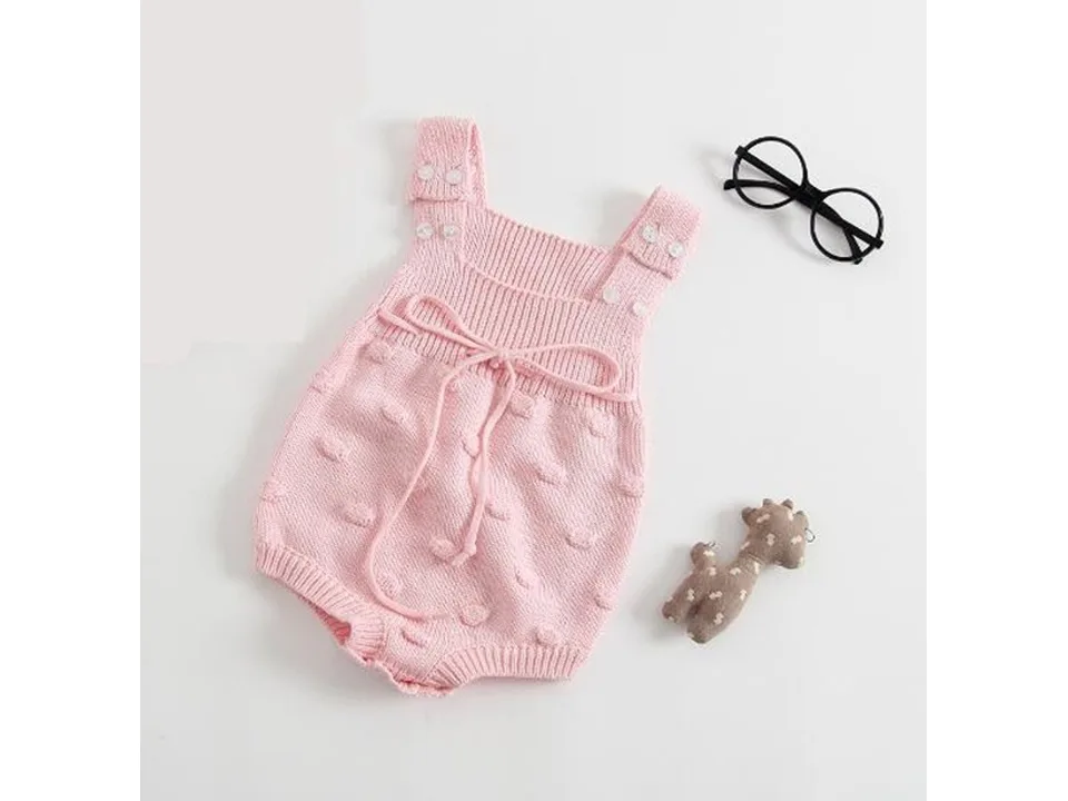 Pink baby knit romper with tie detail and textured dots.