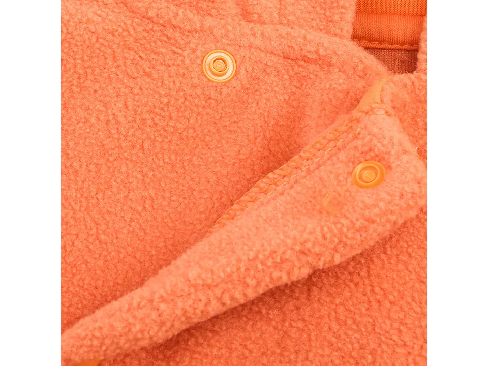 Close-up of orange snap buttons on the front of an orange fleece baby jumpsuit.