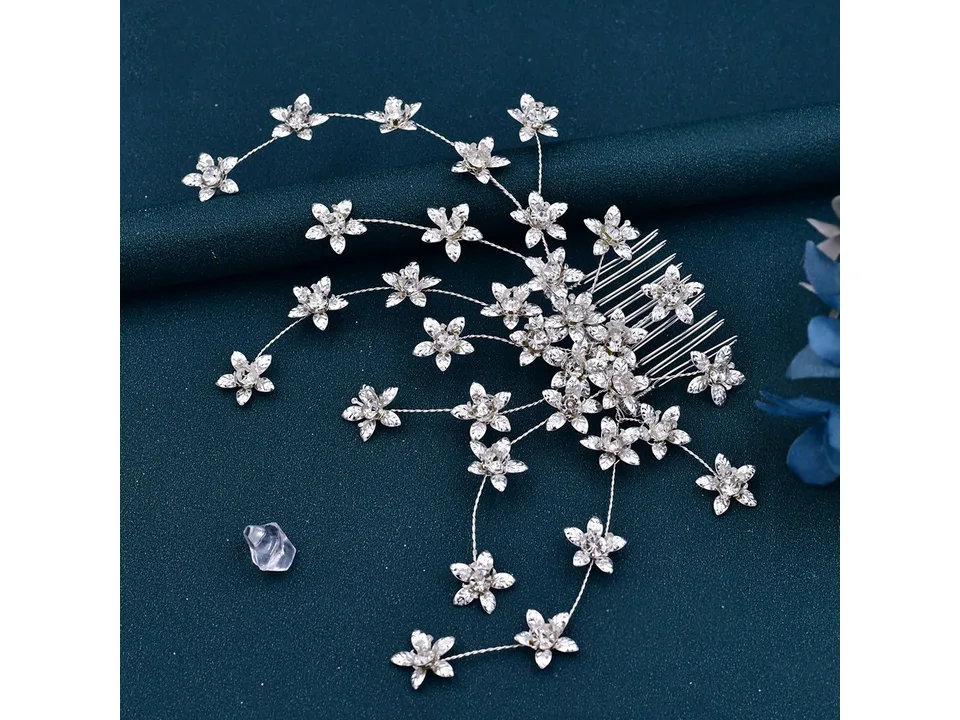 A silver rhinestone flower hair comb on a dark background.