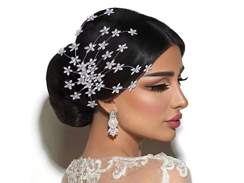 A bride with an updo hairstyle wearing a rhinestone flower hair comb.