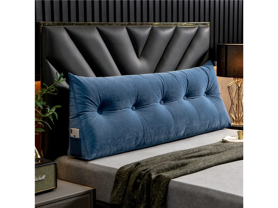 Blue velvet triangle bed headboard pillow with side pocket on a bed.