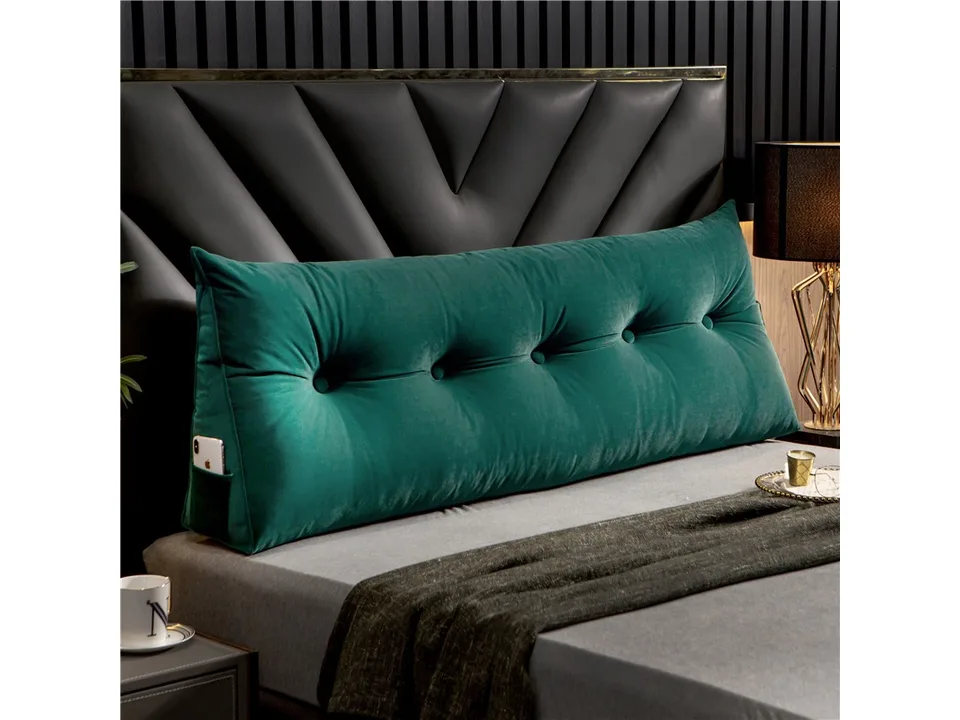Green velvet triangle bed headboard pillow with side pocket on a bed.