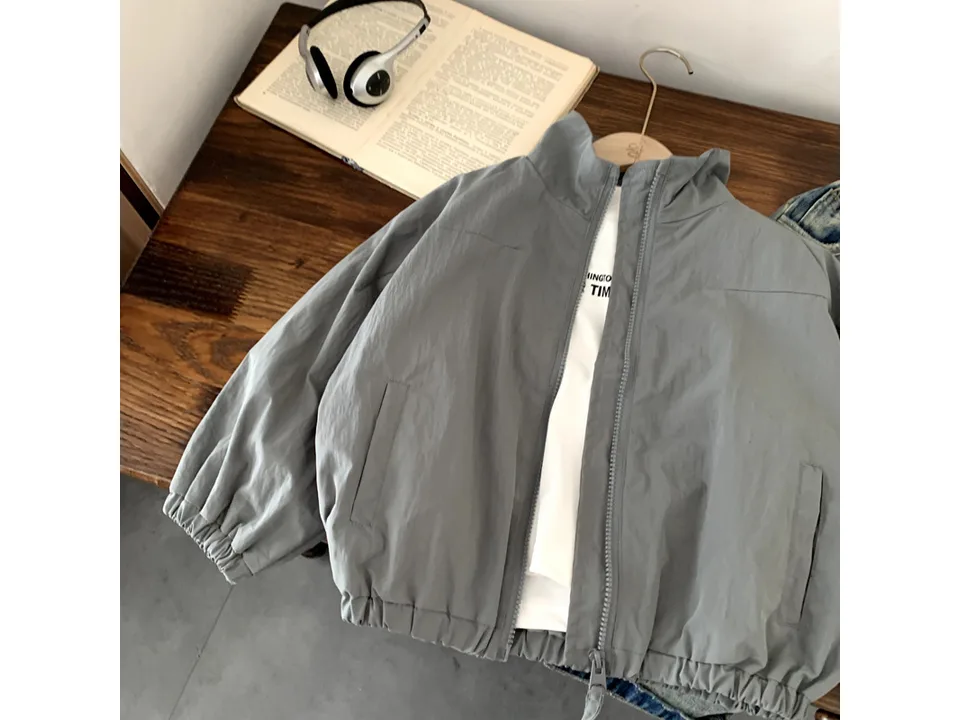 A grey zip-up jacket laid flat on a wooden surface.