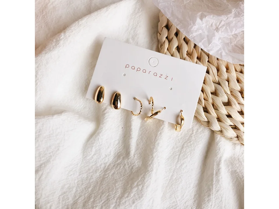 A set of gold-tone earrings attached to a white display card.
