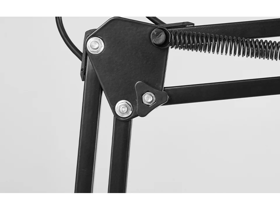 Close-up of the adjustable metal joint and tension spring on the lamp arm.