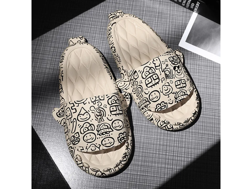 A pair of beige shark-themed slides with black doodle patterns.