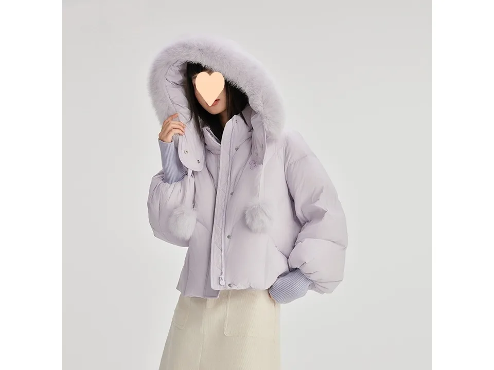 A woman wearing a light-colored short down jacket with the fur-trimmed hood up.