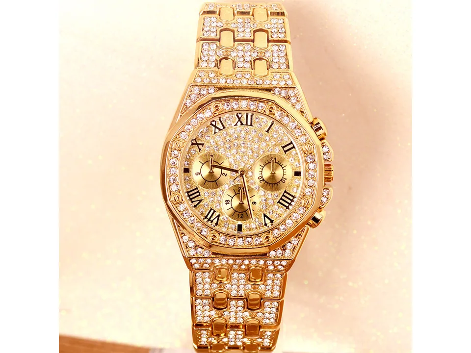 Gold-tone rhinestone-encrusted men's watch on a light background.