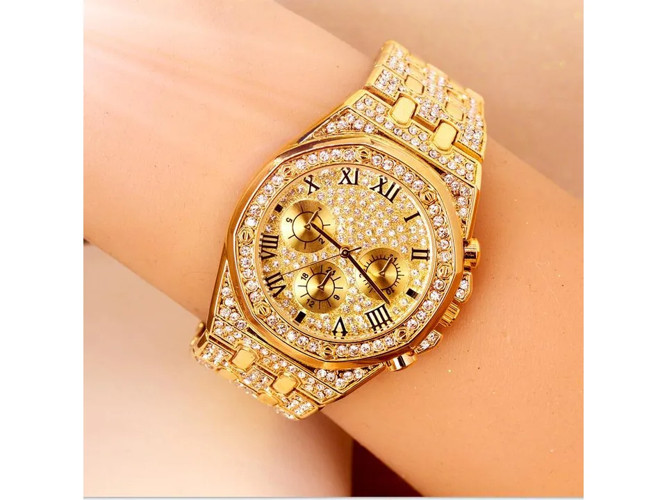 Close-up of a gold-tone rhinestone-encrusted men's watch on a wrist.