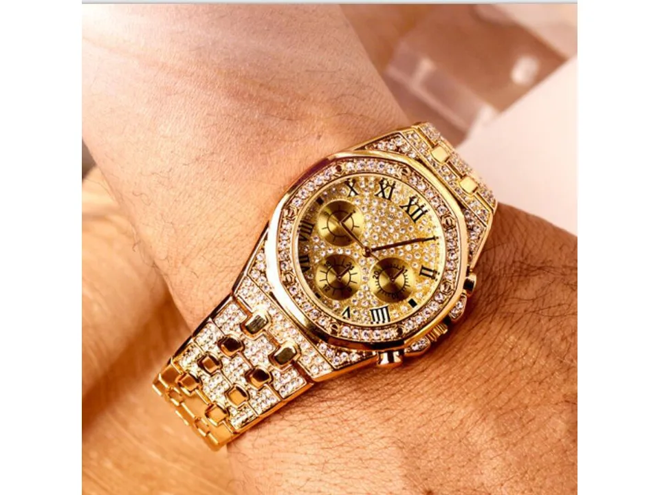 Gold-tone rhinestone-encrusted men's watch worn on a wrist.