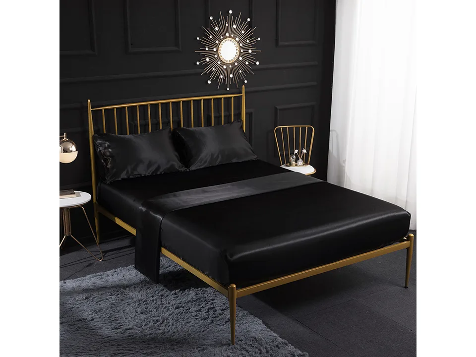Black silk satin bed sheet set on a bed with a gold frame.