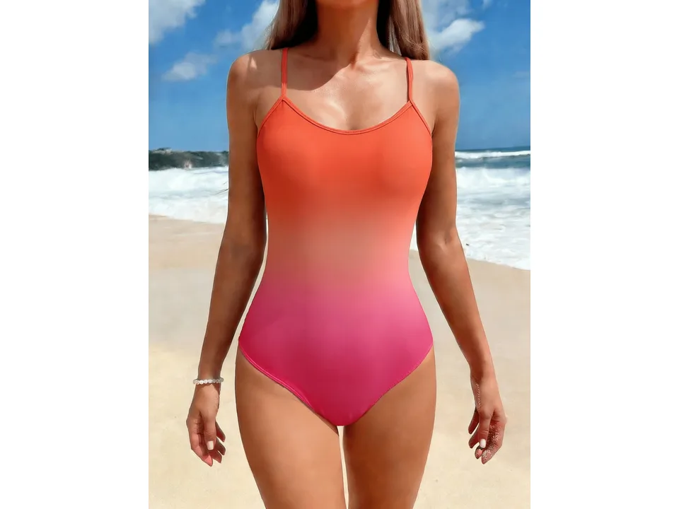 A woman wearing an orange to pink ombre one-piece swimsuit on a beach.