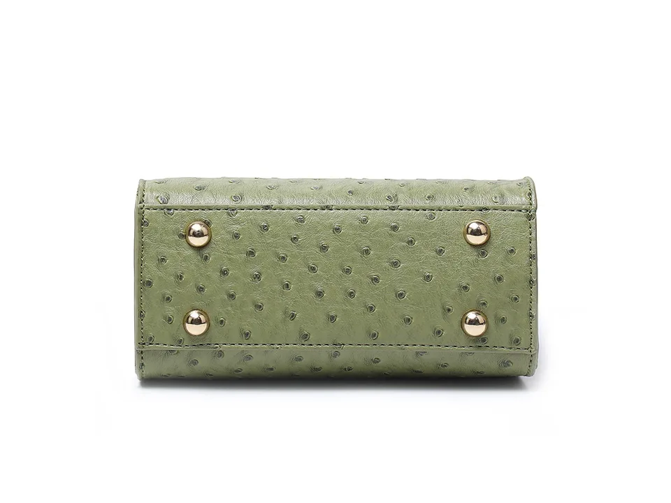 Bottom view of the green handbag showing four protective metal feet