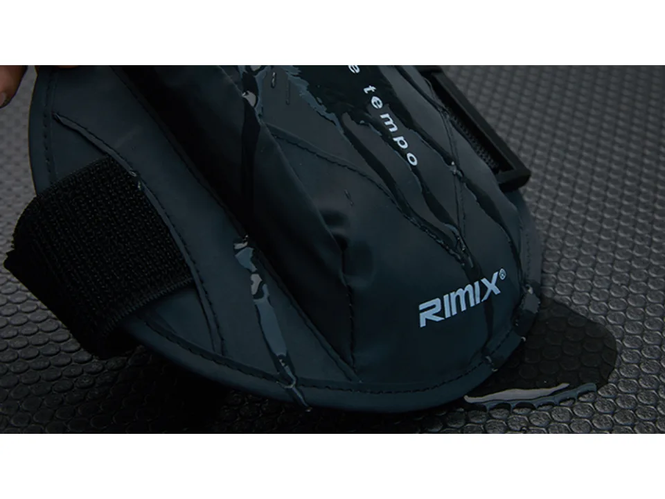 Water being poured over the black sports arm bag to show water resistance.