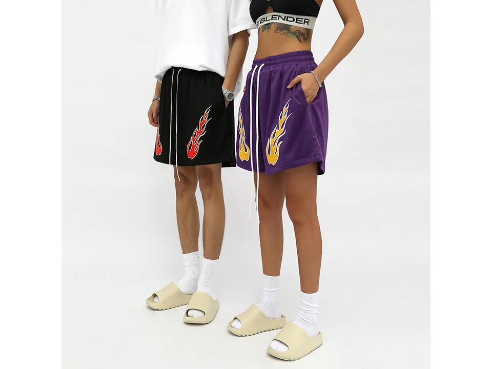 Two models wearing black and purple flame athletic shorts.