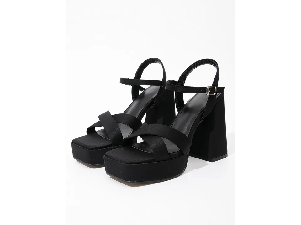 A pair of black suede platform sandals with chunky high heels on a white background.