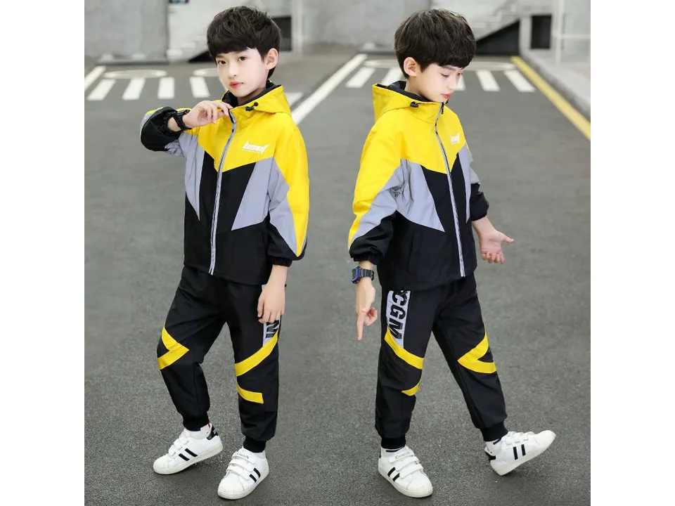 A boy wearing a yellow, grey, and black hooded jacket and matching trousers.