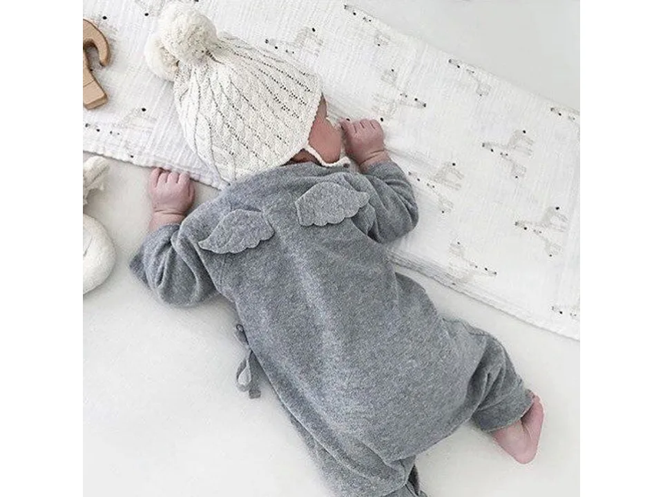 Baby wearing a grey angel wing jumpsuit and a knitted hat.