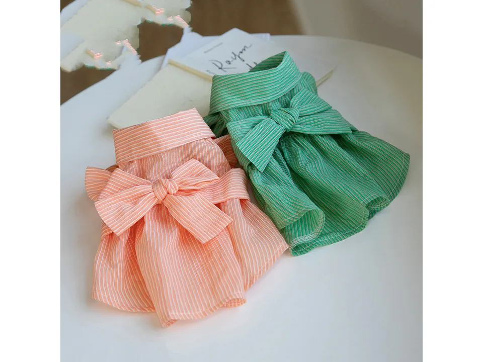 The orange and green striped pet dresses laid out side by side.