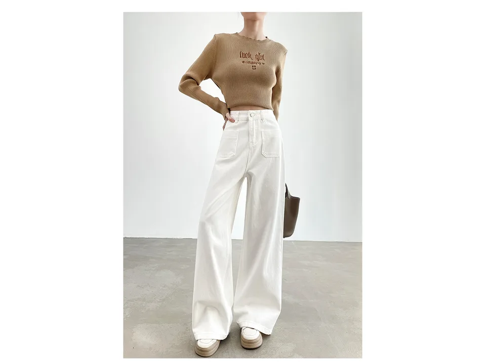 A woman wearing white high-waisted wide-leg denim pants with a brown ribbed top.