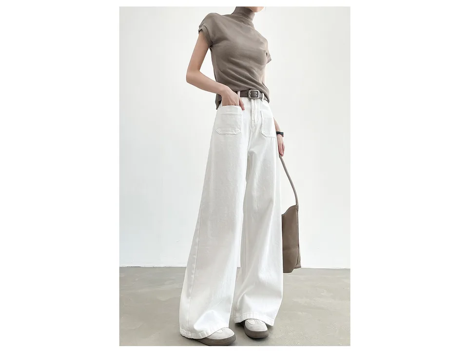 A woman wearing white high-waisted wide-leg denim pants with a brown top and a belt.