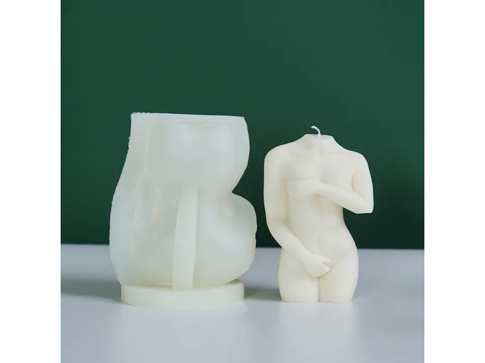 A silicone candle mold next to a finished female torso candle.