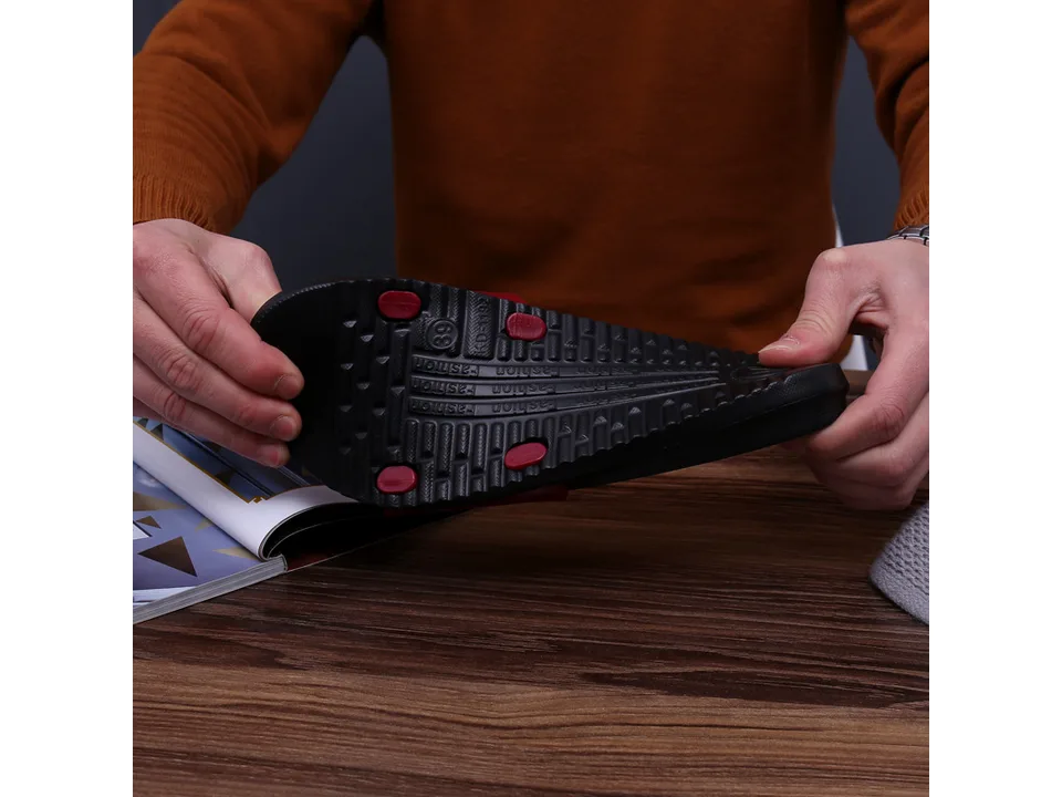 Hands holding a slipper to demonstrate the flexibility and texture of the sole.