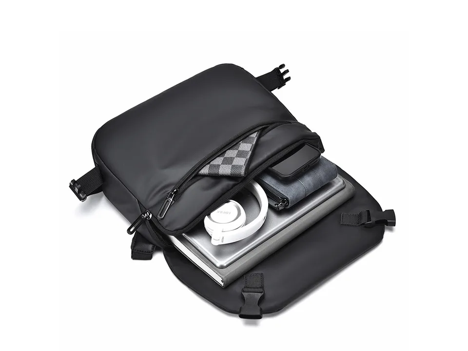 Open crossbody bag showing organized storage for a laptop, headphones, and wallet.