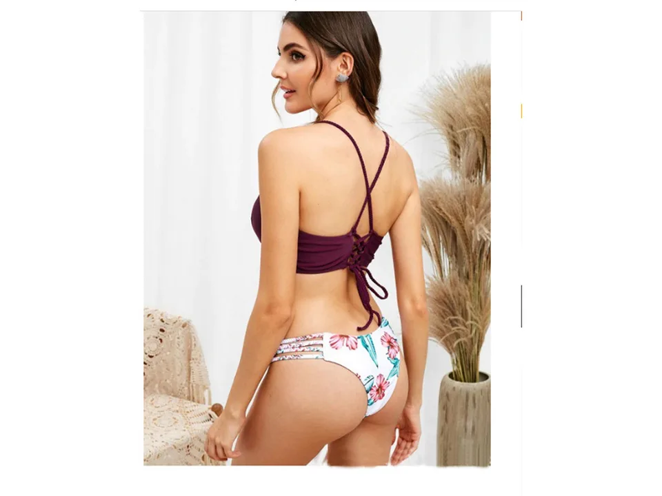 A woman wearing a dark purple bikini top and floral print bottoms, showing the back strap detail.
