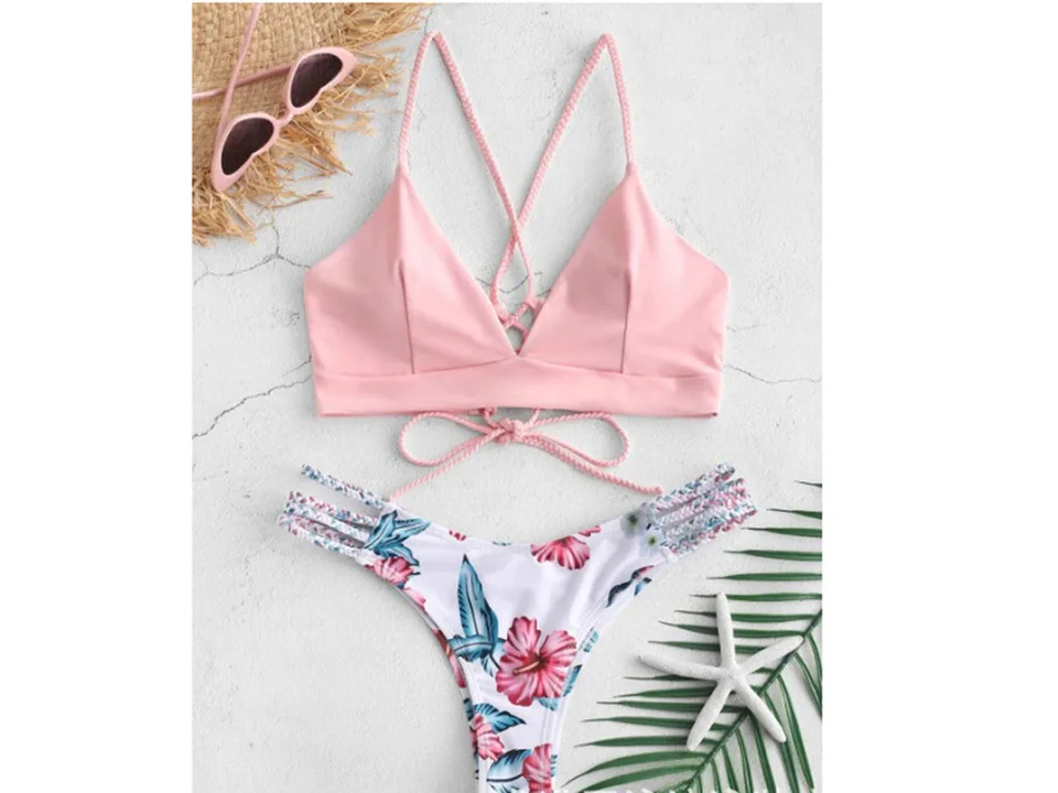 A pink bikini top and floral print bottoms with braided straps, displayed with sunglasses and a starfish.