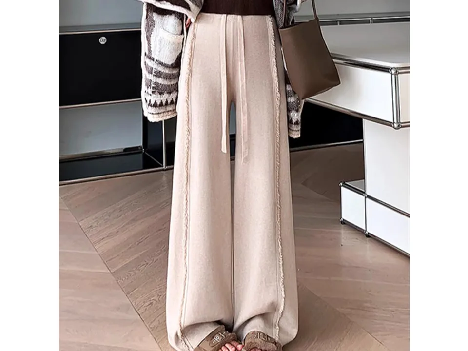Full-length view of beige high-waisted knitted trousers.
